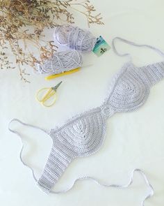 two crocheted bikinisuits are next to scissors and some flowers on a table