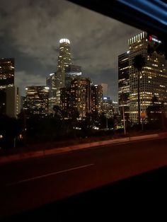 the city skyline is lit up at night as seen from a moving train window with dark clouds