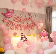 a birthday party with balloons, cake and streamers in pink and white colors on the bed