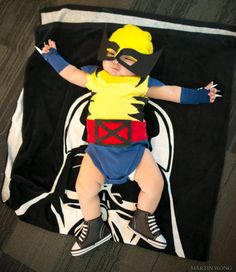 a baby dressed up in a costume laying on top of a black and white blanket