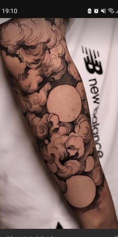 a man's arm with clouds and sun tattoo on the back of his arm