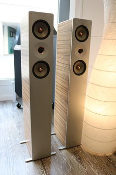 two speakers sitting next to each other on a wooden floor