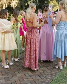 a group of women standing next to each other on top of a brick floored walkway