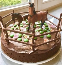 a chocolate cake with horse figurines on top and flowers in the icing