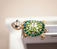 a close up of a ring with a turtle on it's back and green stones