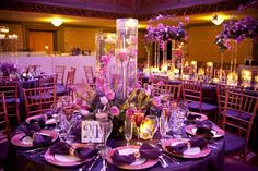 the tables are set with purple and gold plates, silverware, and centerpieces