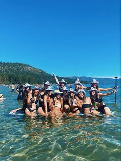 a group of women in bikinis and hats are posing for a photo on a paddle board