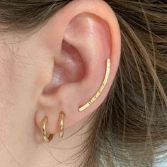 These ear climber earrings are made of 18k gold-plated silver. The hammered wire with a fine texture is slightly curved following the contour of the ear. 🌼 Nickel-free. Made from ethical and recycled 950 solid silver. MEASUREMENTS: ✔️ Length: 24 mm. ✔️ Width: 1.7 mm. ✔️ Ear wire: 0.9 mm. They are very comfortable. Simply pass the wire through the ear hole, turn and position it on the natural curve of the ear. Perfect for everyday wear, single or in combination with other earrings. ✔️ Sold alone Gold Ear Climbers For Everyday, Everyday Gold Ear Climbers, Delicate Gold Pierced Ear Climbers, Delicate Gold Ear Climbers, Gold Minimalist Ear Climbers, Gold Minimalist Pierced Ear Climbers, Gold Ear Crawlers, Ear Wrap Earrings, Ear Sweeps