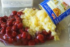 someone is pouring sauce on some food in a glass dish with potatoes and cranberries