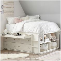 a white bed with drawers underneath it and a rug on the floor next to it