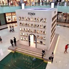 people are walking around in an indoor shopping mall with many displays on the walls and floor