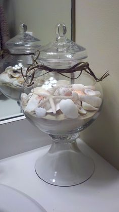 a glass bowl filled with sea shells on top of a counter