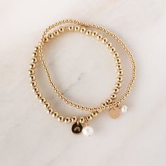 Charmed to meet you! Our easy to wear Tiny Beaded Stretch Bracelet + our best selling Tiny Initial Charm = perfection! This bracelet can be purchased with or without the freshwater pearl charm. Let us know in the Personalized Box what initial or symbol you'd like stamped on the disc charm, or if you'd prefer it to be l Pearl Cuff Bracelet, Pearl Cuff, Gold Bead Bracelets, Jewelry Lookbook, Personalized Bracelets, Pearl Pendant Necklace, Pearl Charms, Birthstone Charms, Charm Set