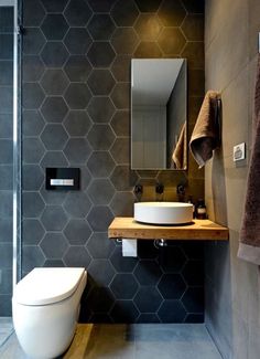 a modern bathroom with hexagonal tiles on the walls and floor, along with a toilet