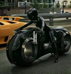 a man riding on the back of a motorcycle down a street next to yellow cars