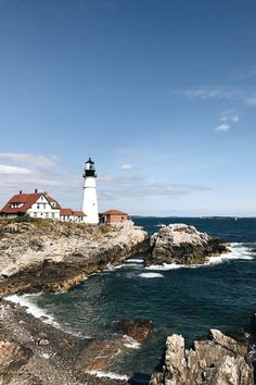 a light house sitting on top of a rocky cliff next to the ocean with waves coming in