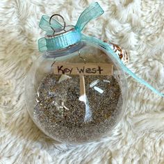 a glass ornament with a key west message in it on a white blanket