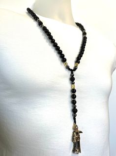 a black beaded necklace on a mannequin with an elephant charm hanging from it