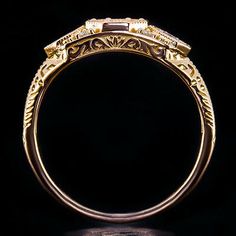 an ornate gold ring with two stones on it's sides and the center stone is surrounded by filigree leaves