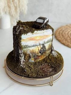 there is a cake with a painting on it and a toy car on the top