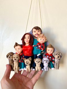 a hand is holding a family ornament with dogs and people hanging from it