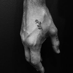 a person's hand with a small flower tattoo on the left side of it