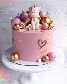 a pink cake with gold decorations and a unicorn on top