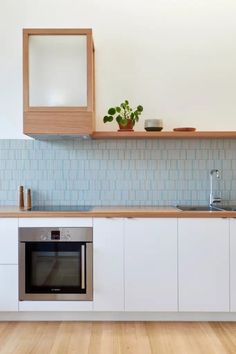 a kitchen with white cabinets and wood flooring next to a window above the sink