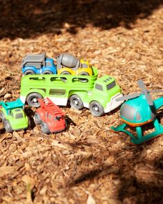 small toy cars are sitting on the ground in front of some wood mulchs