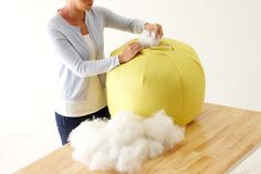 a woman standing next to a large stuffed animal on top of a wooden table with cotton balls