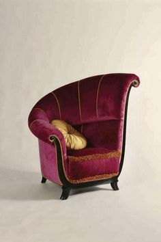 a purple chair with gold pillows on it's arm and back rests against a white wall