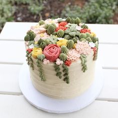 a cake with flowers on it sitting on top of a white table next to a window