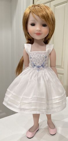 the doll is wearing a white dress and pink shoes