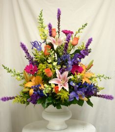 a white vase filled with lots of colorful flowers