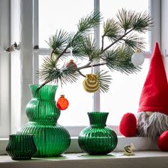 three green vases sitting on a window sill next to a christmas tree with ornaments