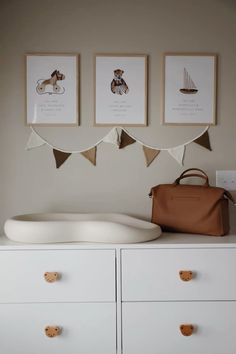 a white dresser with three pictures above it