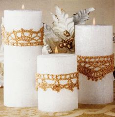 three white candles with gold lace on them