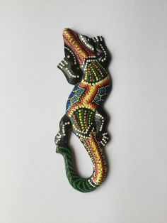 a colorful lizard brooch sitting on top of a white table next to a wall