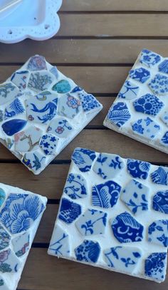 four blue and white tiles sitting on top of a wooden table