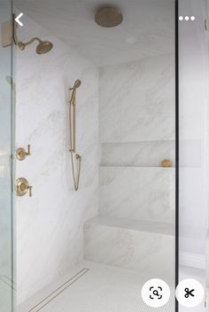 a bathroom with white marble walls and floor, shower head, and shelves in the corner