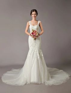 a woman in a wedding dress holding a bouquet and posing for the camera with her hands on her hips