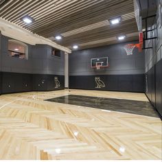 an indoor basketball court with hard wood floors and black painted walls is seen in this image