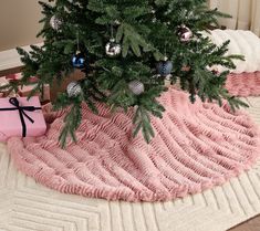 a small christmas tree with ornaments on it and a pink present box under the tree