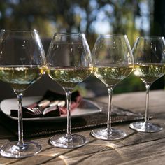 four wine glasses sitting on top of a wooden table