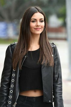 a woman with long hair wearing a black top and leather jacket