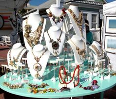 there are many necklaces on display at the market table in front of the house