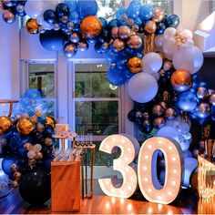 balloons and lights decorate the entrance to a 30th birthday party in blue, gold and white