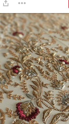 an embroidered fabric with gold and red flowers on it