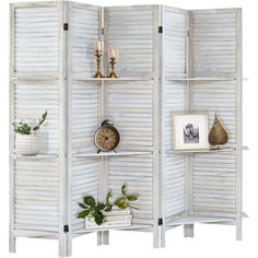 a white room divider with three shelves on each side and plants in the middle