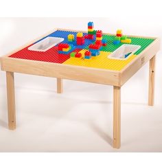 a child's wooden table with legos and cups on the top, sitting against a white background